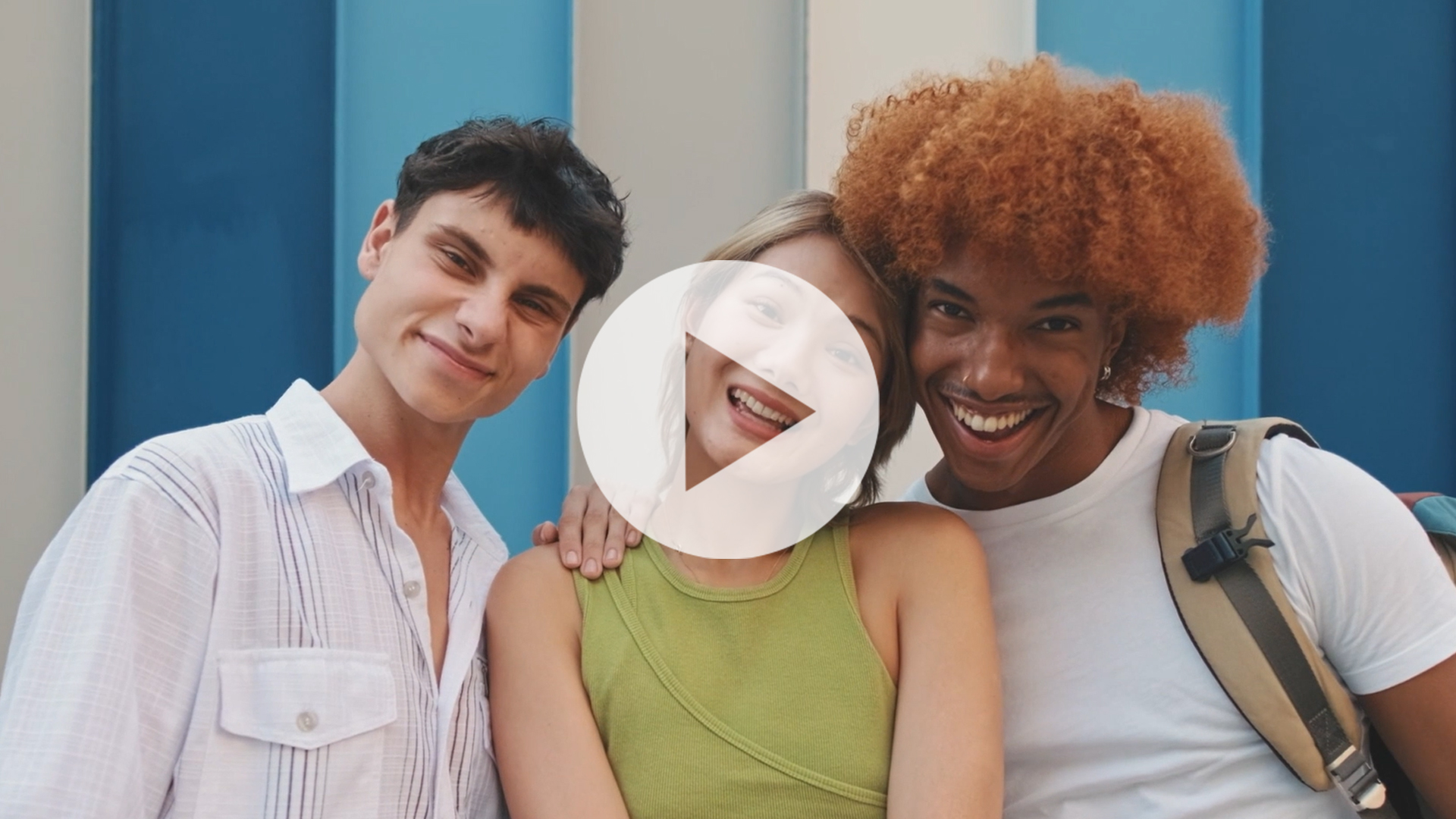 Video thumbnail featuring three smiling young adults standing together in front of a blue-striped wall. A large play button overlays the center of the image, indicating the video can be played.
