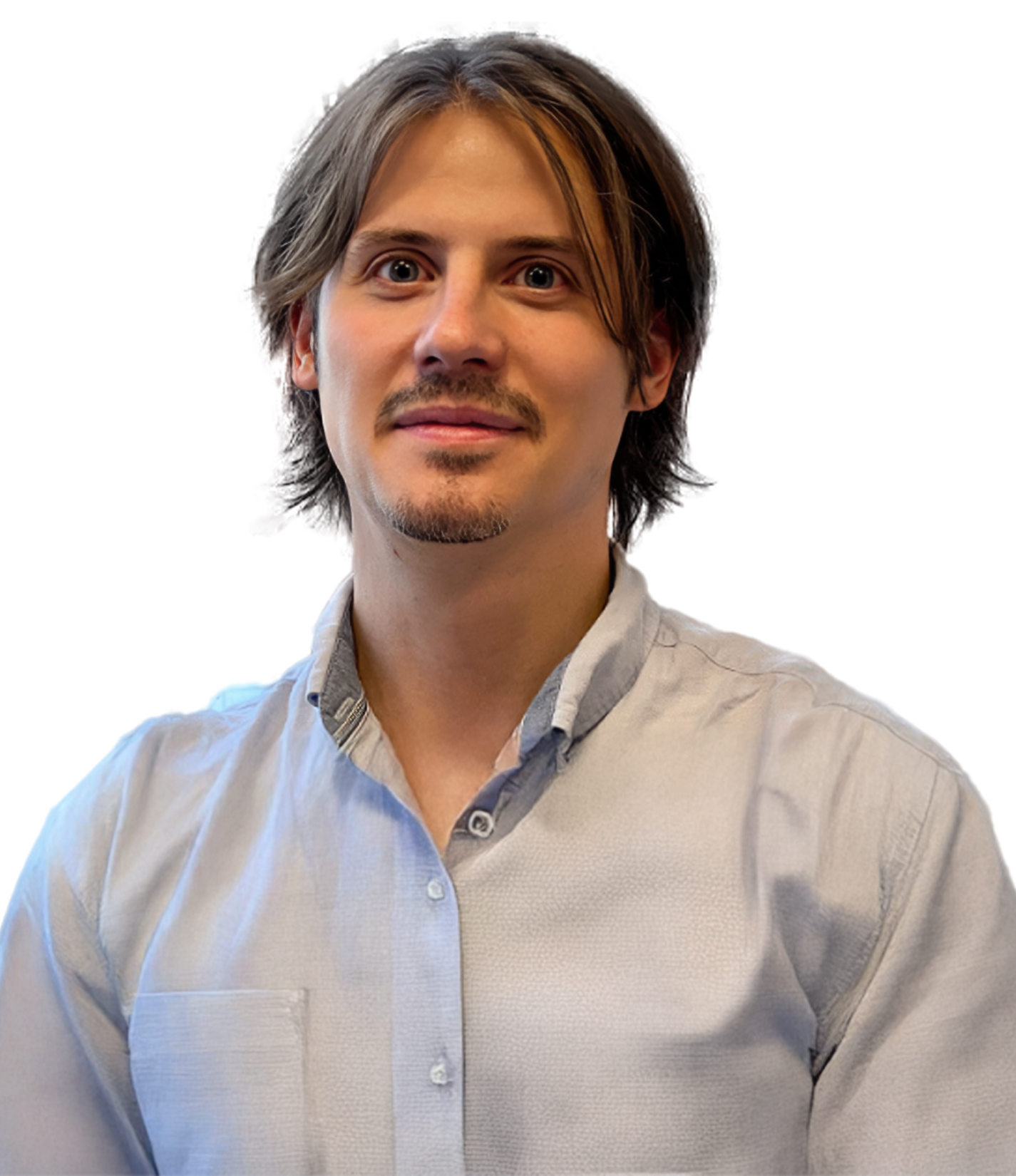 A man with medium-length light brown hair and a short goatee, wearing a light blue button-down shirt, looking into the camera against a white background.