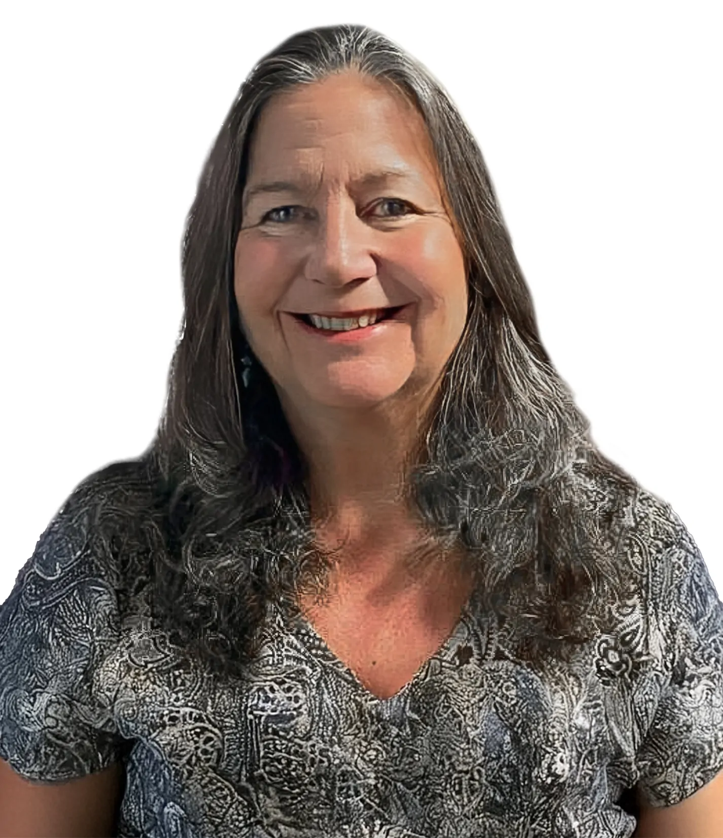 A woman with long wavy gray hair wearing a patterned blouse, smiling against a white background.