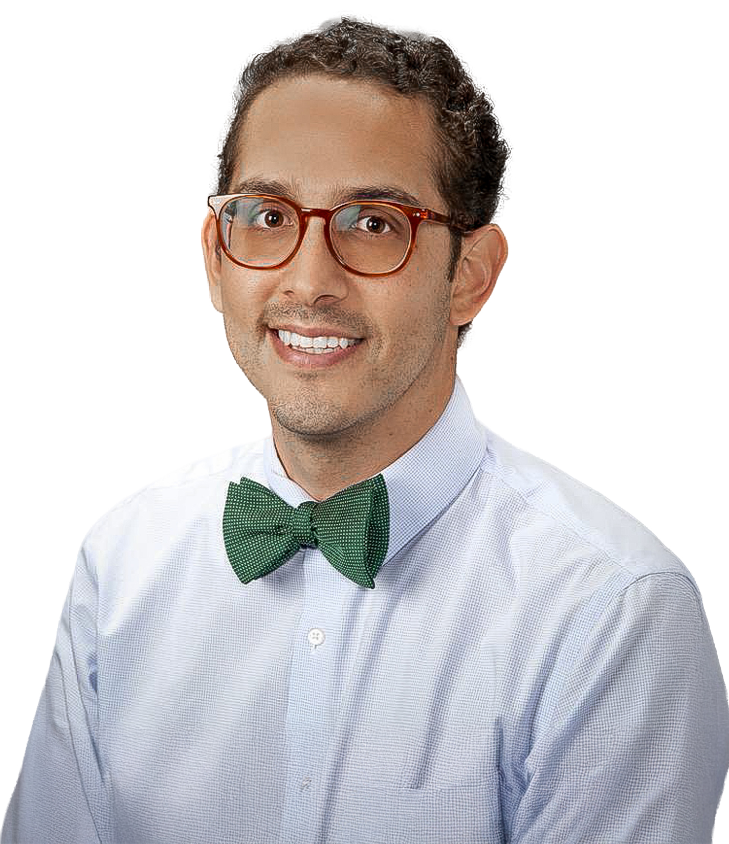 A man with short dark curly hair and glasses wearing a light blue shirt and green bow tie, smiling against a white background.