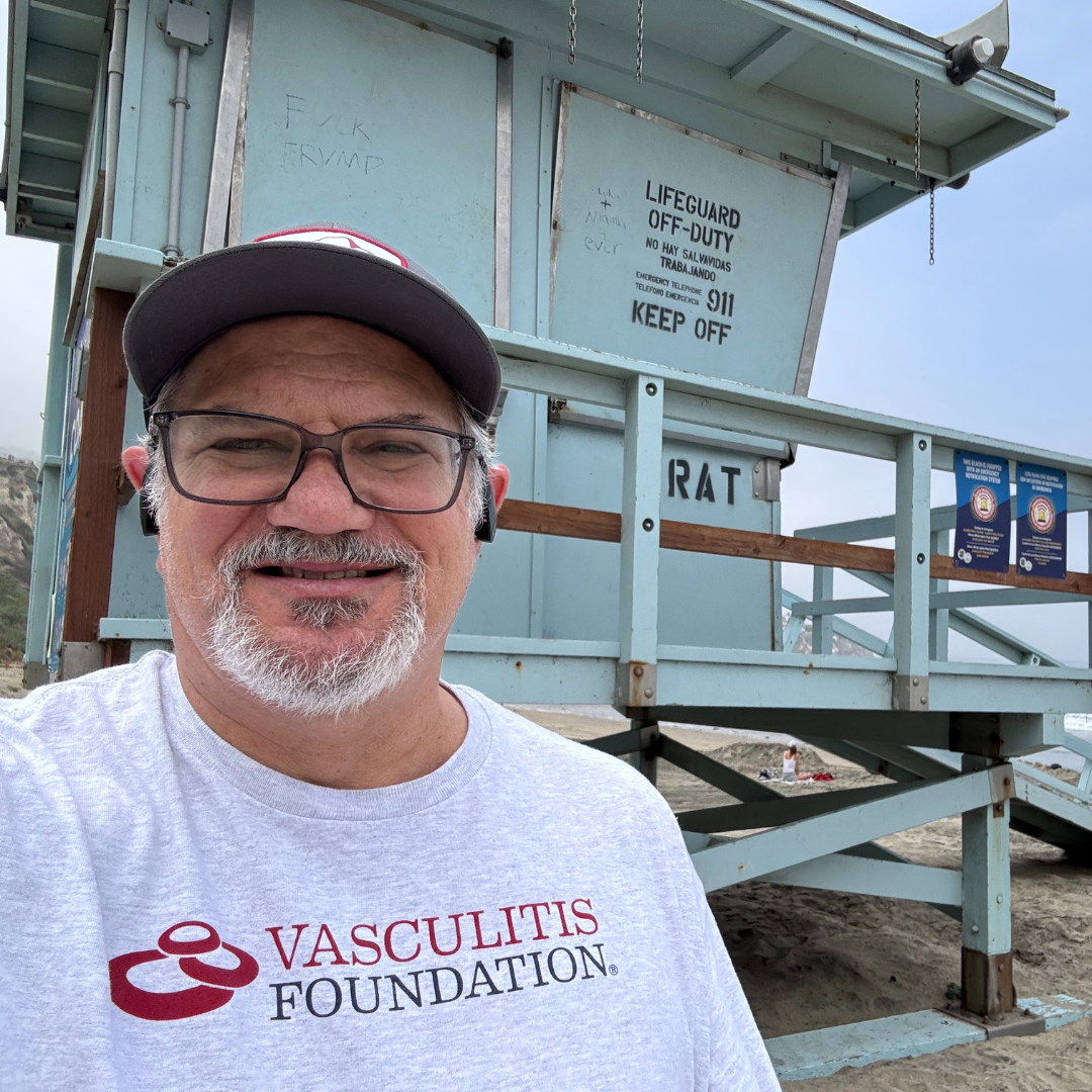 David pictured smiling at the beach wearing a Vasculitis Foundation t-shirt.