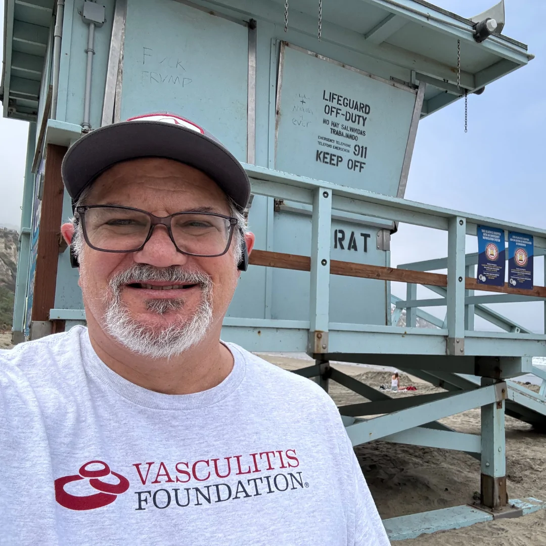 David pictured smiling at the beach wearing a Vasculitis Foundation t-shirt.
