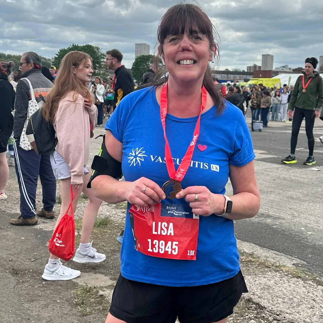 Lisa picture outside smiling with medal after finishing 10k race. 