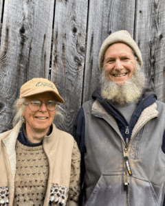 Anne and Eric standing outside smiling in front of a wooden fence