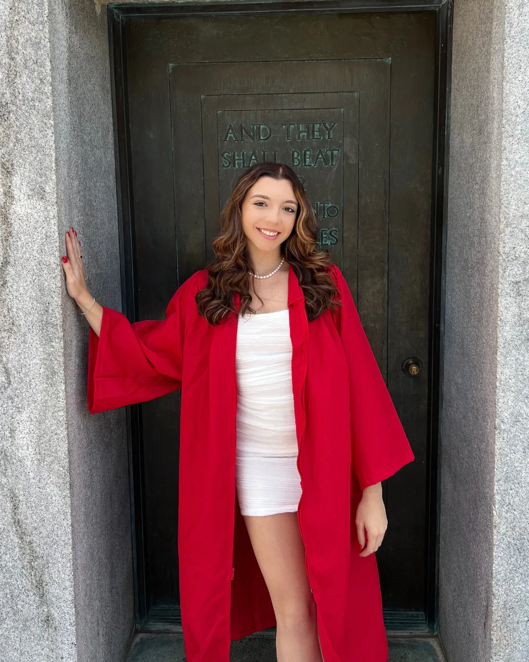 Jenna posing with red graduation gown on graduation day