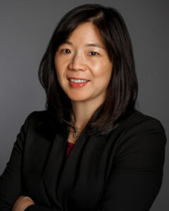 Professional headshot of a woman with shoulder-length dark hair wearing a black blazer.