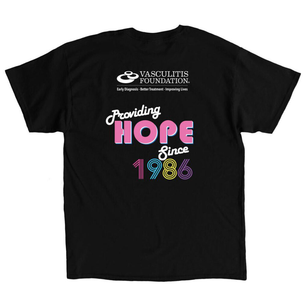 Back of a black T-shirt featuring the Vasculitis Foundation logo and the phrase “Providing Hope Since 1986” in colorful lettering.