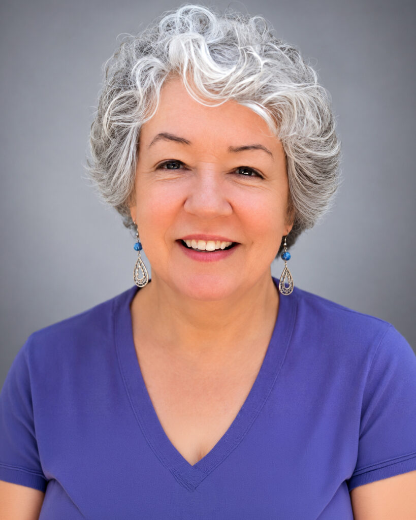 Smiling woman with short curly gray hair wearing a purple top
