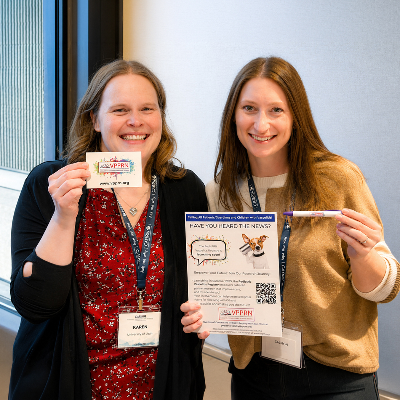 Two women smile while displaying promotional materials for the Pediatric Vasculitis Patient-Powered Research Network (PedsVPPRN), including a flyer, information card, and pen.