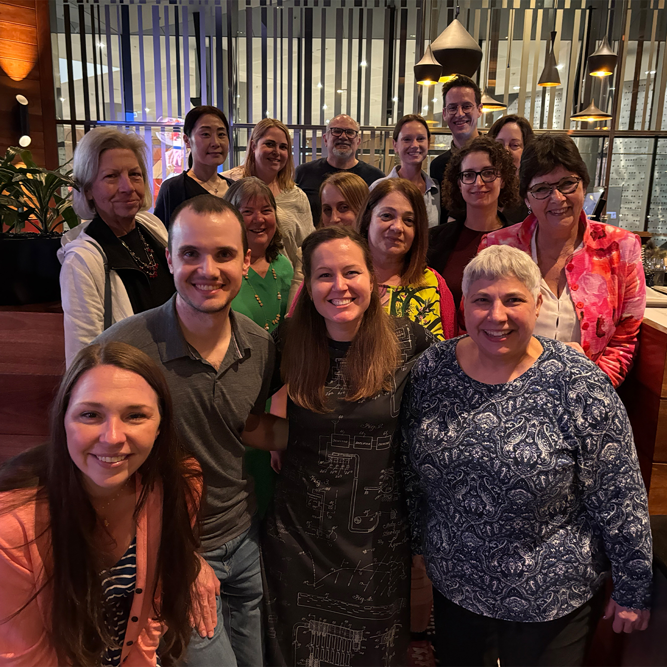 Group of conference attendees and advocates smile for a photograph together inside a restaurant during a gathering in Australia.