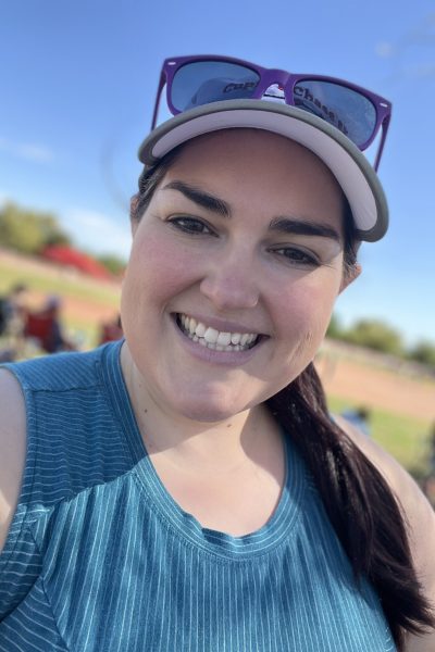 Megan pictured outside smiling with a hat and sunglasses