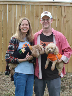 Patricia and her husband pictured smiling outside with their two small dogs on Thanksgiving