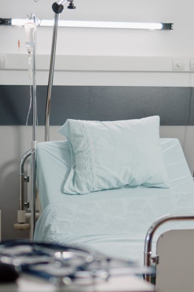 Empty bed in hospital ward with medical equipment for healthcare and recovery. Nobody in reanimation room with heart rate monitor and IV drip bag for intensive care and assistance.